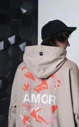 Hoodie oversize color gris topo, confeccionado en rústico de algodón, con capucha forrada, bolsillo canguro y costuras expuestas en mangas y ruedo. Presenta estampa gráfica en la espalda con la palabra AMOR y diversos motivos románticos.