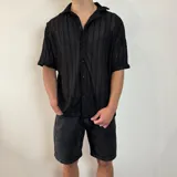 Camisa de manga corta confeccionada en tejido de crochet con diseño de rayas verticales, cuello solapa y cierre frontal con botones.
