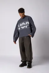 Buzo oversize de corte boxy, confeccionado en algodón rústico de alto gramaje en color beige. Presenta cuello redondo con borde crudo, mangas largas y una estampa frontal con el texto VCP delimitado por líneas horizontales blancas.