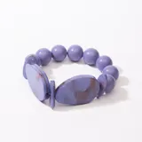 Pulsera elástica con cuentas redondas y ovaladas de resina color lila con detalles marmolados en marrón.
