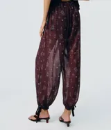 Pantalón largo estilo Aladino de Blue Steel, confeccionado en chiffon con estampado floral y detalles de encaje aplicado. Cuenta con cintura elástica y bajos ajustables con amarras en los tobillos.