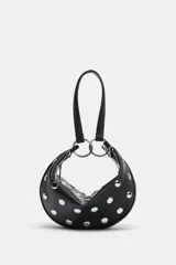 Bolso de mano tipo saca con diseño redondeado, confeccionado en material sintético color marrón oscuro. Presenta múltiples tachas metálicas doradas distribuidas por toda la superficie y un asa superior sujeta por anillas metálicas doradas. Cuenta con cierre superior mediante cremallera metálica.