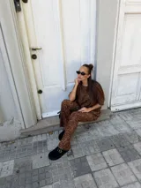 Conjunto de dos piezas compuesto por una remera de manga corta y un pantalón de corte acampanado, ambos confeccionados en lanilla con estampado animal print en tonos marrones.