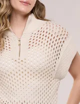 Buzo de punto color marfil, confeccionado en algodón calado con cuello alto acanalado y medio cierre metálico dorado. Presenta mangas cortas estilo japonesa con puños anchos y un zócalo acanalado en el ruedo.