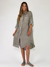 Camisola midi confeccionada en lino color gris, con diseño amplio y fluido, cuello camisero, cierre frontal con botones y mangas largas con presilla para arremangar.