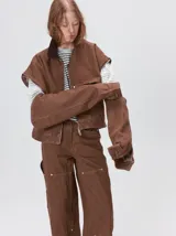 Campera de denim a rayas verticales con cuello de pana en color bordó. Presenta cierre frontal, mangas desmontables con cierre en los hombros, canesú en el pecho y bolsillos de parche cuadrados.