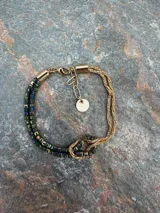 Pulsera de oro de 18k con diseño de cadena tipo serpiente doble y un nudo central decorativo. Cuenta con cierre de mosquetón y cadena de alargue con placa grabada.