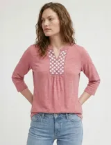 Blusa de manga tres cuartos color rosado, confeccionada en modal texturizado. Presenta un escote en V con cuello a la base y apliques nacarados en el área del escote.