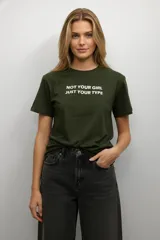 Remera de algodón color verde militar, con cuello redondo, manga corta y estampado frontal con la frase 'NOT YOUR GIRL JUST YOUR TYPE' en color blanco.
