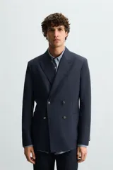 Blazer regular fit color azul marino, confeccionada en tejido con lana. Presenta cuello con solapas de pico, manga larga con puño abotonado, bolsillos de vivo en el pecho y de plastrón en la cadera. Incluye un bolsillo interior y aberturas en la espalda. El cierre es frontal con botonadura cruzada.