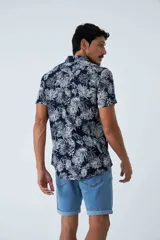 Camisa de manga corta con estampado botánico de hojas en tonos azul y blanco. Presenta cuello clásico, cierre frontal abotonado y corte slim.