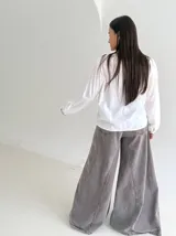 Camisa blanca de manga larga con cuello mao, cierre frontal de botones y detalle de volado. Presenta bordados florales en color marrón chocolate en la parte superior delantera.