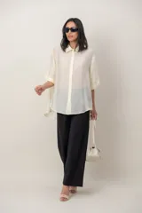 Camisa oversize de seda negra, con cuello camisero, cierre frontal con botones y mangas cortas con vuelta.