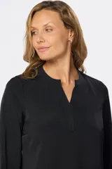 Blusa de manga larga en color azul marino, con escote en V y diseño de doble capa en el frente. Presenta puños elásticos y un pequeño aplique metálico decorativo en el ruedo.
