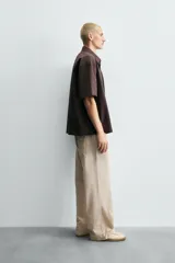 Pantalón relaxed fit color beige con rayas verticales finas, confeccionado en tejido de algodón. Cuenta con cintura elástica ajustable con cordón, bolsillos frontales y bolsillos traseros de plastrón.