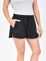 Short negro de tela de buzo, con cintura elástica ajustable con cordón y bolsillos laterales. El ruedo tiene una abertura lateral.