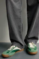 Zapatilla deportiva de estilo retro en color verde, confeccionada en una combinación de piezas de cuero y gamuza, con detalles a contraste en tono tostado y suela de goma dentada.