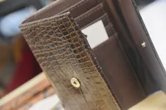 Billetera de cuero marrón con estampado de piel de serpiente, con cierre de broche a presión.