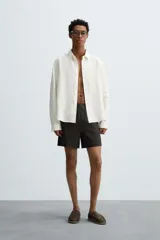 Bermuda de corte relajado confeccionada en tejido de lino color gris oscuro. Presenta cintura elástica con cordón de ajuste interno, bolsillos laterales y bolsillos traseros de plastrón.