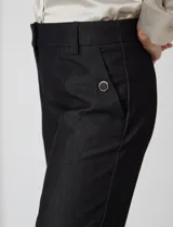 Pantalon de corte cigarette en color beige, confeccionado en tejido con apariencia denim y acabado satinado. Presenta tiro medio-alto, largo tobillero, cintura con presillas, cierre con gancho sastrero oculto, bolsillos laterales diagonales con botones forrados y pinzas traseras para un ajuste entallado.