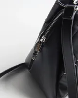 Cartera de símil cuero negro con diseño matelassé romboidal y tachas metálicas plateadas. Cuenta con dos asas de mano, correa bandolera regulable y desmontable, compartimento central con cierre y herrajes plateados con logo XL.