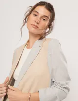 Blazer oversized de corte recto en lino, color beige y gris. Largo a la cadera, con hombreras finitas forradas, costuras internas con sesgo combinado y bolsillos delanteros.