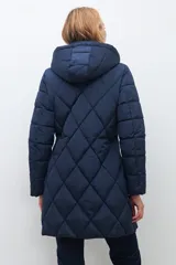 Campera acolchada de largo medio, color azul marino, con diseño de rombos. Posee cuello alto y capucha desmontable.