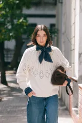 Sweater de lana tejido en color crudo, con cuello redondo y diseño calado en la zona del pecho y espalda. Presenta un corte holgado y puños acanalados.