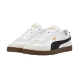 Championes Puma modelo Club Li Era, con diseño de perfil bajo en color negro, franja lateral blanca característica de la marca y suela de goma color caramelo. Presenta detalles en dorado en el logo lateral y la lengüeta.