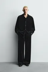 Sobrecamisa de corte relajado confeccionada en tejido de terciopelo elástico, con cuello solapa, manga larga con puños abotonados y cierre frontal de botones.