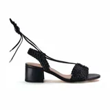 Sandalia de cuero sintético negro con tiras trenzadas, taco bloque y ajuste con tiras para atar al tobillo.