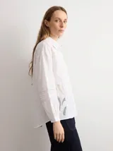Camisa amarilla de manga larga con detalles bordados y calados en los hombros, pecho y mangas, corte clásico con cuello camisero y cierre frontal de botones.