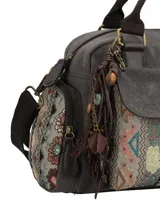 Cartera tipo bandolera de color gris con diseño patchwork étnico en el bolsillo frontal. Cuenta con doble asa superior, correa ajustable y removible, múltiples bolsillos con cierre y un llavero decorativo con borlas y cuentas.
