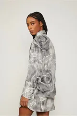 Camisa blanca con estampado de pata de gallo en negro, abotonada en el frente y de corte recto.