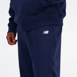 Pantalón tipo jogger New Balance de corte holgado, confeccionado en tejido elástico color azul marino. Presenta cintura con cordón de ajuste interno, puños elásticos en los tobillos y logo bordado en la parte superior de la pierna.