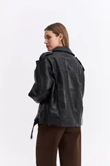 Campera estilo biker de cuero sintético negro con cierre frontal cruzado, solapas amplias, bolsillos con cierre y cinturón ajustable en la base.