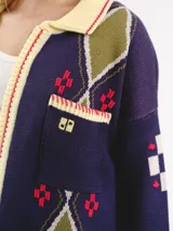 Campera tejida en jacquard con cierre frontal, cuello tipo polo y bolsillos delanteros. Diseño multicolor con estampado geométrico de rombos y detalles bordados a mano.