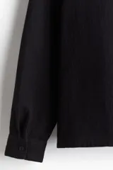 Camisa de manga larga en tejido de algodón con textura, corte regular fit, cuello inglés, bolsillo frontal y bajo recto.
