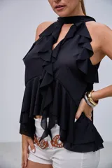 Blusa negra con cuello halter y escote en V, adornada con volados en el frente y en el bajo. Diseño asimétrico y tiras largas que caen por la espalda.
