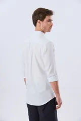 Camisa de lino a rayas finas en tonos beige y blanco, de manga larga con puños vueltos, cuello camisero y cierre frontal de botones. Cuenta con un pequeño logo bordado en el pecho.