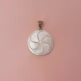 Dije colgante circular de nácar con un diseño grabado que simula una flor de cinco pétalos. El reverso es de plata 925 con una argolla decorada para pasar la cadena.