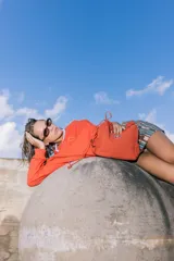 Bolso de nylon color naranja quemado, con textura sutil y manija fruncida. Presenta un parche rectangular negro con el logo 'KUL.' en blanco en el frente.