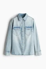 Camisa de denim color celeste claro, de manga larga, con cuello clásico, botones a presión dorados en el frente y puños, canesú en la espalda y dos bolsillos superiores con solapa y botón a presión.
