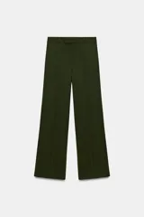 Pantalón de tiro medio color verde militar, con pernera recta, trabillas en la cintura y cierre frontal con cremallera, botón interior y ganchos metálicos ocultos.