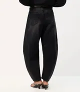 Pantalón baggy balloon de jean negro, de tiro medio con bolsillos delanteros y traseros, recortes estructurales y botamanga ajustada. Incluye cinto de poliuretano con hebilla metálica.