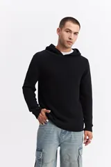 Canguro de punto negro con capucha, de corte relajado y textura acanalada. Presenta puños y ruedo tejidos.