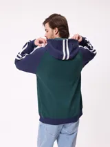 Canguro con capucha de estilo deportivo, con cuerpo en color celeste y mangas raglán en color negro. Presenta el logo de la marca estampado en el pecho, bolsillo tipo canguro frontal y franjas blancas laterales en las mangas.