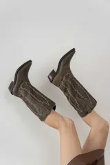 Bota de cuero color marrón con bordado decorativo en el caño, taco bajo y punta fina.