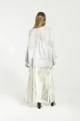 Camisa de viscosa y seda gris, de corte boxy y diseño semitransparente. Posee cuello mao, cierre frontal con botones, mangas largas con puños, bolsillos grandes en el frente y detalles de satén.