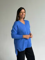 Sweater de tejido de punto color azul, con escote en V, manga larga con puños acanalados y diseño holgado con costura central vertical y ruedo asimétrico.